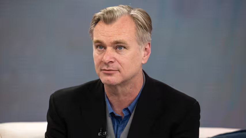 Director Christopher Nolan in a dark blazer and blue shirt during a TV interview