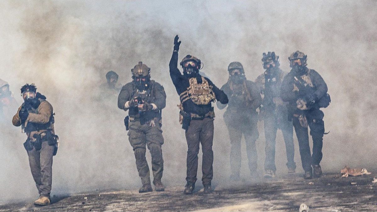 Police in gas masks advancing through tear gas during the unrest in Minneapolis